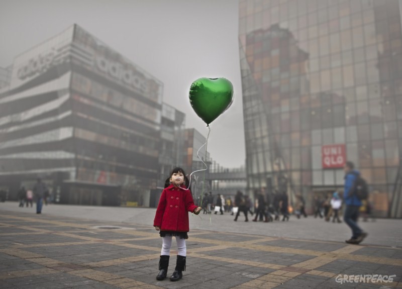 空气污染严重，一个小女孩手持气球站在污染的空气中。这个孩子鼻子接着呼吸管，通往气球中仅剩的空气里